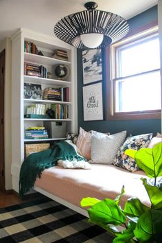 a living room with a couch, bookshelf and plants in the window sill