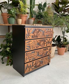 a wooden dresser sitting next to potted plants