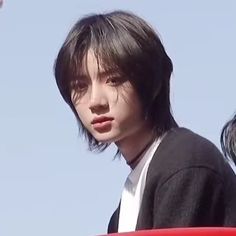 a young man sitting in the back of a red car