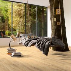 a bedroom with wood flooring and large windows overlooking the trees in front of it