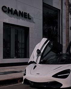 a white sports car parked in front of a chanel store with its doors open