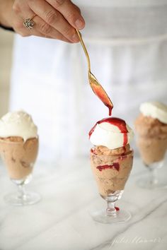 a person is spooning ice cream out of an ice cream sundae with strawberries and whipped cream