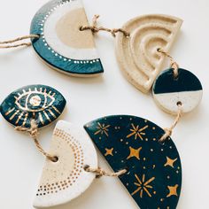 three ceramic ornaments are hanging from twine strings on a white surface with gold stars