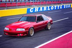 a red car driving down a race track with the word charlotte usa on it's side