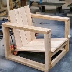 a wooden chair sitting on top of a floor next to some construction tools and pliers