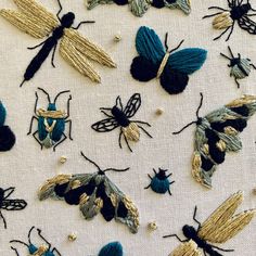 embroidered bugs and moths on white fabric with gold threads, sequins and beads