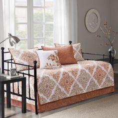 a day bed with orange and white comforters in a room next to a window