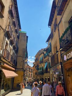 people are walking down the street in an old european city with many buildings and balconies