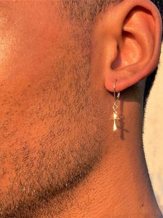 a close up of a man's ear wearing gold earrings with small cross on it