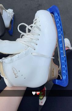 a pair of ice skates being held up by someone's hand with their feet on them