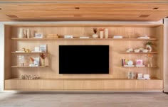 a living room with wooden shelves and a flat screen tv mounted to the side of it