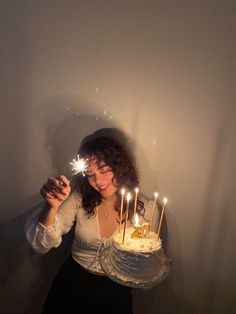 a woman holding a cake with lit candles