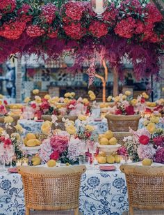 an outdoor dining area with wicker chairs and tables covered in flowers, lemons and red carnations