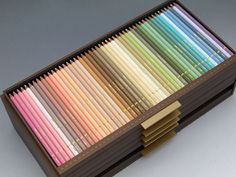 a wooden box filled with lots of colored pencils