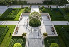 an aerial view of a formal garden with trees and shrubs in the center, surrounded by grass