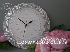 a white clock sitting next to pink flowers