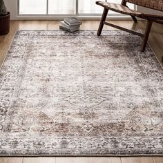 a large rug with an ornate design on the floor in front of a wooden chair