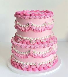 a three tiered cake with pink icing and ruffles