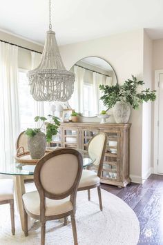 a dining room table with white chairs and a chandelier hanging from the ceiling