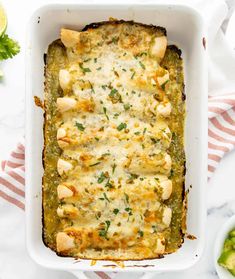 a white casserole dish filled with chicken and cheese, garnished with parsley