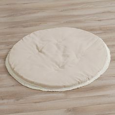 a round dog bed on top of a wooden floor