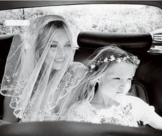 a bride and her father in the back seat of a car with their flower girl