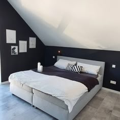 a large bed sitting in the middle of a bedroom under a slanted ceiling with two lamps on each side