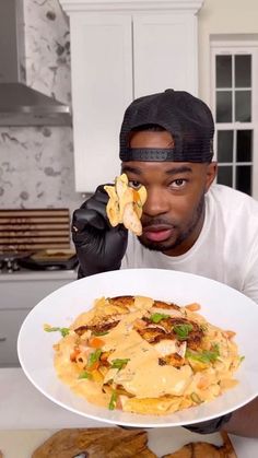 a man holding a plate with food on it in front of his face and looking at the camera