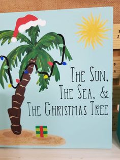 a christmas card with a palm tree and santa's hat on it, sitting on a shelf