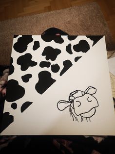 a drawing of a cow is shown on a piece of paper with black and white spots