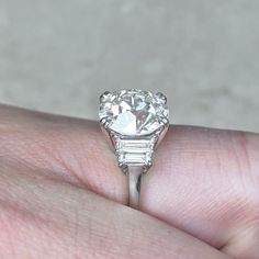 a close up of a person's hand holding a ring with a diamond on it