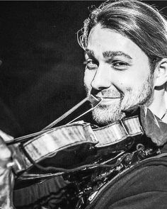 a man with long hair holding a violin in his hand and smiling at the camera