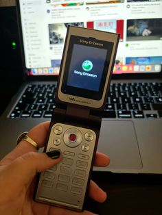 a person holding a cell phone in front of a laptop