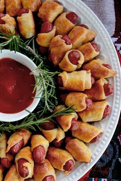 a white plate topped with pigs in a blanket and dipping sauce