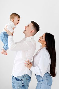 a man and woman holding a baby up in the air