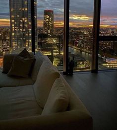 a living room filled with furniture next to tall buildings at night time and looking out onto the city