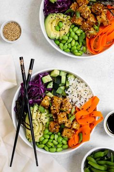 two bowls filled with vegetables and meat next to chopsticks on a white surface