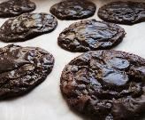 chocolate cookies are lined up on a sheet of wax paper and ready to be baked