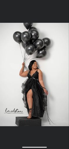 a woman in a black dress holding balloons