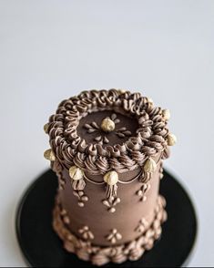 a three layer chocolate cake with decorative decorations on it's top, sitting on a black plate