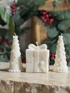 three small white christmas trees sitting on top of a stone table next to each other