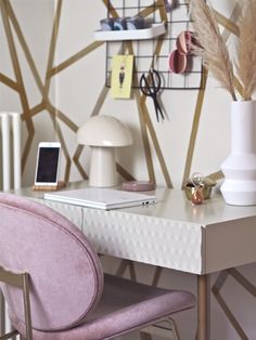 a white desk topped with a laptop computer next to a pink chair and wallpaper