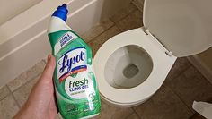 a person holding a bottle of toilet cleaner next to a toilet