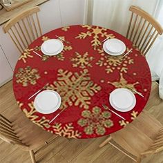 a red table with gold snowflakes on it and white plates sitting at the top