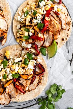 three tacos with chicken, peppers, and cheese on them next to cilantro