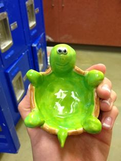 a hand holding a green ceramic turtle figurine