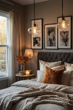 a bed sitting under two framed pictures next to a window with candles on top of it