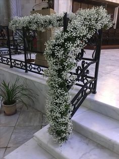 white flowers are growing on the steps in front of a church entranceway with wrought iron railings