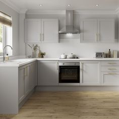 a kitchen with white cabinets and wood flooring is pictured in this image, there are no people around