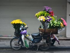 a motor scooter with flowers on the back parked in front of a building